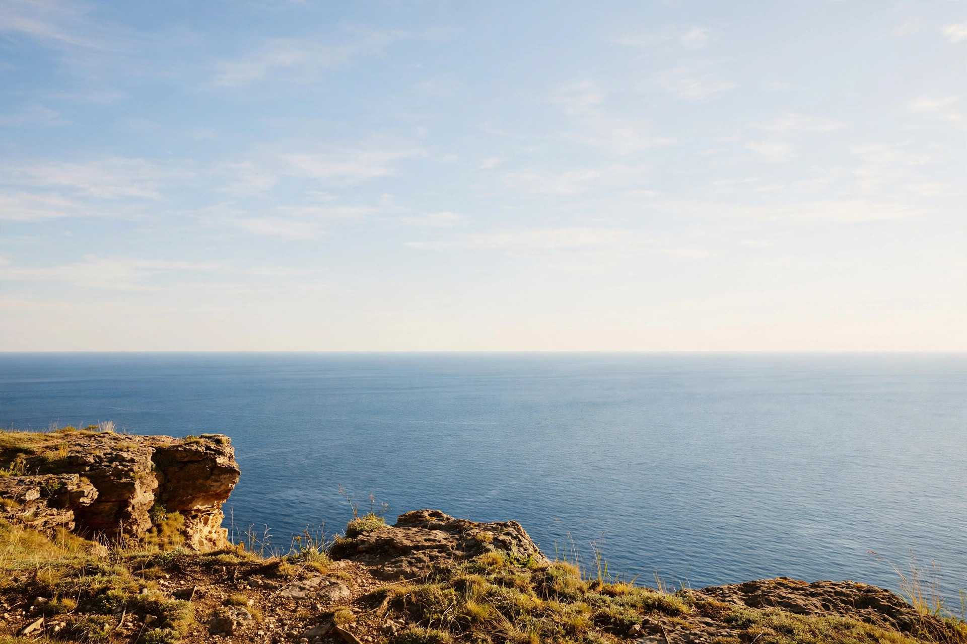 View from a high sea cliff over the endless ocean in summer sunshine